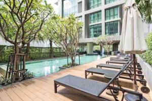 a hotel pool with lounge chairs and an umbrella at Luxurious in Prime Area Bangkok (PickupService) in Bangkok