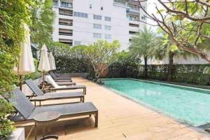 a swimming pool with chaise lounges and chairs next to a building at Luxurious in Prime Area Bangkok (PickupService) in Bangkok