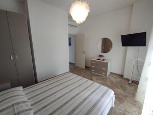 een slaapkamer met een bed, een spiegel en een televisie bij Miramare Apartments in Otranto