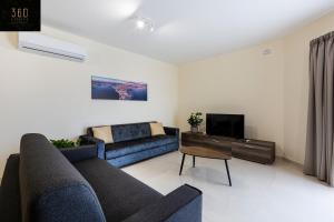 - un salon avec deux canapés bleus et une télévision dans l'établissement Serene 2BR Apartment with Picturesque Views by 360 Estates, à Marsaxlokk