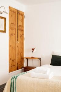 - une chambre avec un lit et une porte en bois dans l'établissement Casa do Lado, à Vila Nova de Milfontes