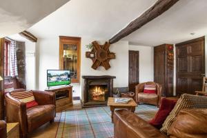 a living room with a fireplace and a tv at The Coppermines Mountain Cottages - Sawyers, Carpenters, Pelton Wheel, Sleeps 18 in Coniston