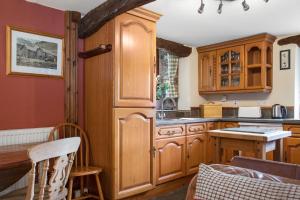 una cucina con mobili in legno e tavolo di The Coppermines Mountain Cottages - Sawyers, Carpenters, Pelton Wheel, Sleeps 18 a Coniston Altre 28 foto