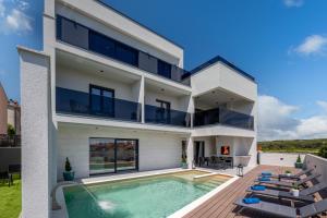 a white house with a swimming pool and chairs at Luxury Wellness & Spa Villa Depaja in Zadar
