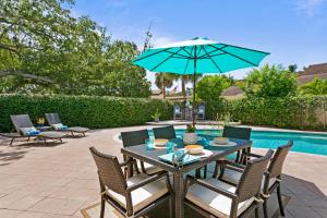 a patio with a table and chairs and an umbrella at Saltwater & Sun Pool / Fire Pit / Family Arcade in Tampa