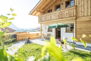 een houten huis met een patio met een parasol bij Waldchalets & Ferienwohnungen Allgäu in Burgberg