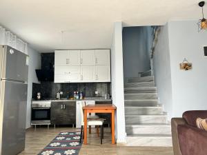 une cuisine avec des placards blancs, une table et un escalier dans l'établissement Duplex Villa With Garden, à Enez