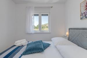 ein weißes Schlafzimmer mit einem Bett und einem Fenster in der Unterkunft Miro's apartments with private garden and parking( town center) in Trogir