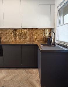 a kitchen with black and white cabinets and a sink at Apartament Nowy Władek 1 in Władysławowo