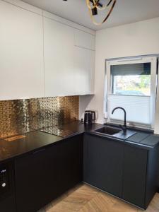 a kitchen with black counters and a sink and a window at Apartament Nowy Władek 1 in Władysławowo
