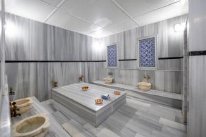 Harmony Hotel Merter & SPA في إسطنبول: حمام به مغسلتين وحوض استحمام ودورتين مياه