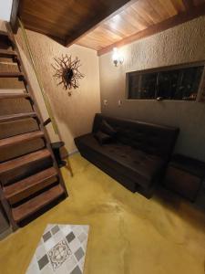 sala de estar con sofá negro y escalera en Chalé tribal, en Alto Paraíso de Goiás