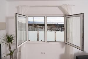 a white room with two windows and a view of a city at Apartamento Marea Viva in Fisterra