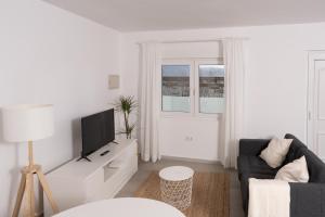 a white living room with a couch and a tv at Apartamento Marea Viva in Fisterra