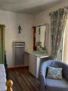ein Badezimmer mit einem Waschbecken, einem Spiegel und einem Stuhl in der Unterkunft Comps sur Artuby, le tilleul et le four, Jabron in Comps-sur-Artuby