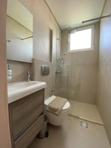 uma casa de banho com um WC, um lavatório e uma janela em Hotel Pavlos - Studios em Tolo