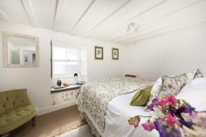 a white bedroom with a bed and a window at Mariners Cottage in Mousehole