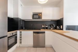 a kitchen with white cabinets and a stainless steel dishwasher at Full House By Plaza in Chessy