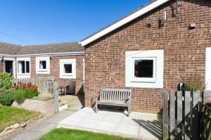 a brick house with a bench in the yard at Rockpool Cottage in Beadnell