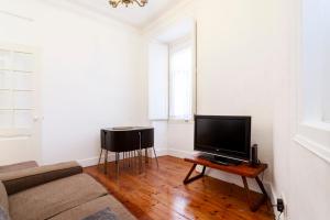 uma sala de estar com um sofá e uma televisão numa mesa em Historical Apartment em Lisboa