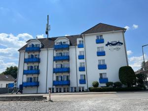 een groot wit gebouw met blauwe balkons erop bij Hotel Aggertal in Gummersbach
