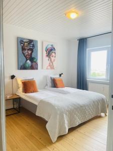 um quarto com uma grande cama branca com pinturas na parede em aday - Modern charming apartment in Noerresundby em Nørresundby