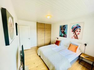 aday - Modern charming apartment in Noerresundby في Nørresundby: غرفة نوم بها سرير ولوحات على الحائط