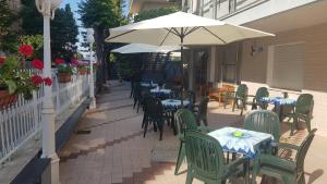 an outdoor patio with tables and chairs and an umbrella at Albergo Rita in Rimini