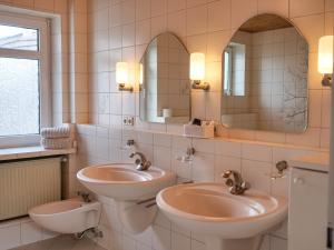 a bathroom with two sinks and two mirrors at PfalzZeit in Weisenheim am Berg