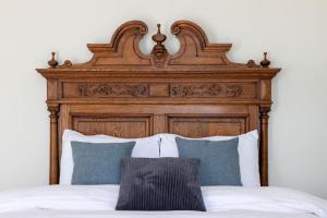 a bed with a wooden head board and pillows at B&B Tannerie in Balen