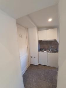 a small kitchen with white cabinets and a sink at Nice 2 bedroom apartment near city center in Rijeka +7 photos
