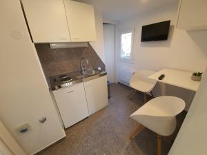 a small kitchen with white appliances and a table and chairs at Nice 2 bedroom apartment near city center in Rijeka