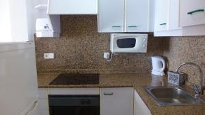 a kitchen with a sink and a microwave at Apartamentos Paradís Palmyra in Salou