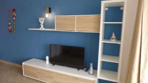sala de estar con TV y pared azul en Apartamentos Paradís Palmyra, en Salou