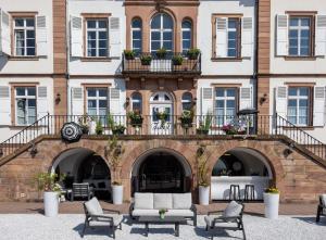 a building with a bunch of chairs in front of it at Hôtel Val-Vignes Colmar Haut-Koenigsbourg, The Originals Relais in Saint-Hippolyte