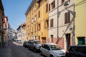 eine Straße mit Autos, die an der Seite eines Gebäudes geparkt sind in der Unterkunft A due passi della casa natale del Maestro Toscanini in Parma