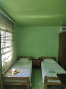 two twin beds in a room with a window at Гостевой дом ИРИНА in Sukhum
