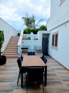 un tavolo e sedie in legno su un patio con scale di Pescoluse Apartments a Marina di Pescoluse