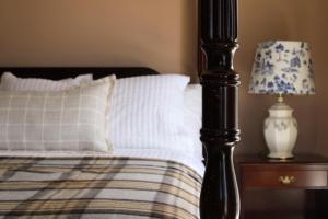 a bed with a white pillow and a lamp on a table at The Cooper's Inn in Shelburne