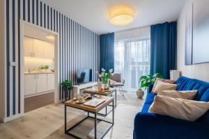 a living room with a blue couch and a kitchen at Deluxe Apartments by The Railway Station Wroclaw in Wrocław