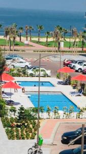 a view of a pool with red umbrellas and the ocean at Porto Said Resort Rentals in Port Said
