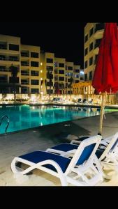 2 sedie a sdraio e un ombrellone accanto alla piscina di Porto Said Resort Rentals a Port Said