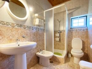 a bathroom with a sink and a toilet and a shower at Casa da Risca in Unhais da Serra