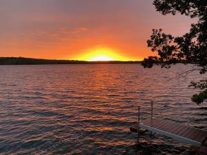 einen Sonnenuntergang auf einem See mit einem Boot im Wasser in der Unterkunft The Burgundy Dream Bed And Breakfast in Fall River