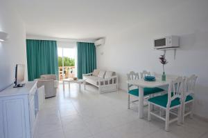 een woonkamer met een tafel en stoelen bij Apartamentos Sol Romántica by DOT Suites in Cala Romantica