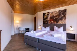 ein Schlafzimmer mit einem großen Bett mit einem Gemälde an der Wand in der Unterkunft Gasthof zur Post Saulgrub in Saulgrub