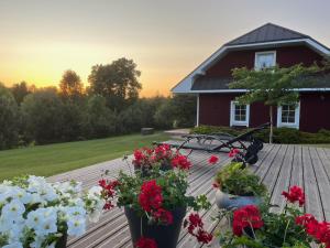a deck with red and white flowers and a house at Villa Sofia Boutique Trakai in Trakai