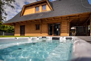 a hot tub in front of a log cabin at Chata Kukaňa in Stará Lesná