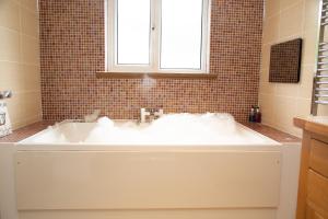 een badkamer met een wit bad en een raam bij Millbrook Lodge in Lake District National Park