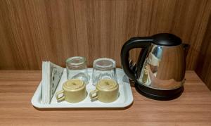 a tray with a tea kettle and glasses on a table at Treebo Trend Hiland Suites in Bangalore